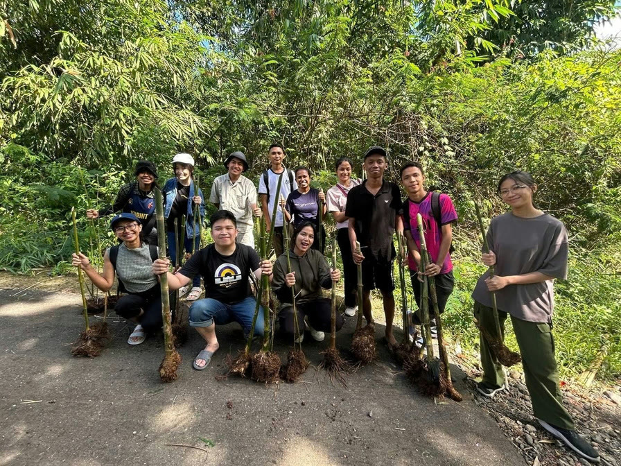 A group of young volunteers in a forest clearing, holding seedlings ready for planting.